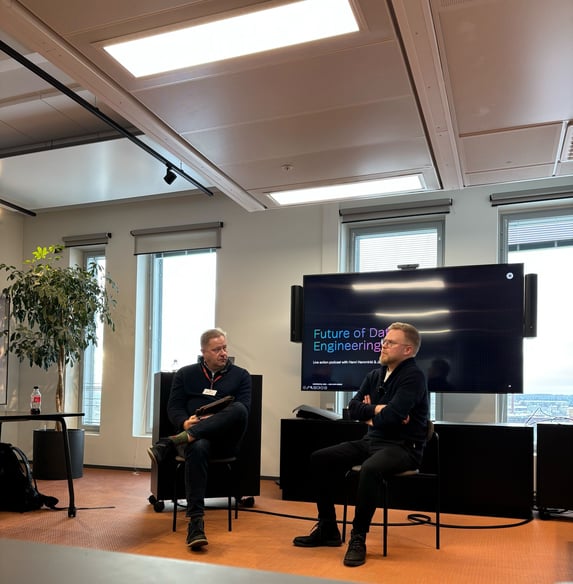 Two men sitting in front of a tv and having a chat